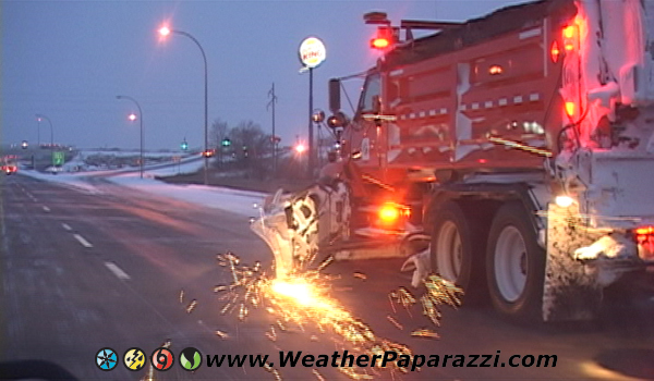 Snow plow with sparks off the blade.